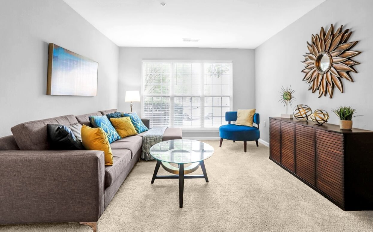 Living room space with sectional sofa, blue armchair and dresser with several elements of decor.