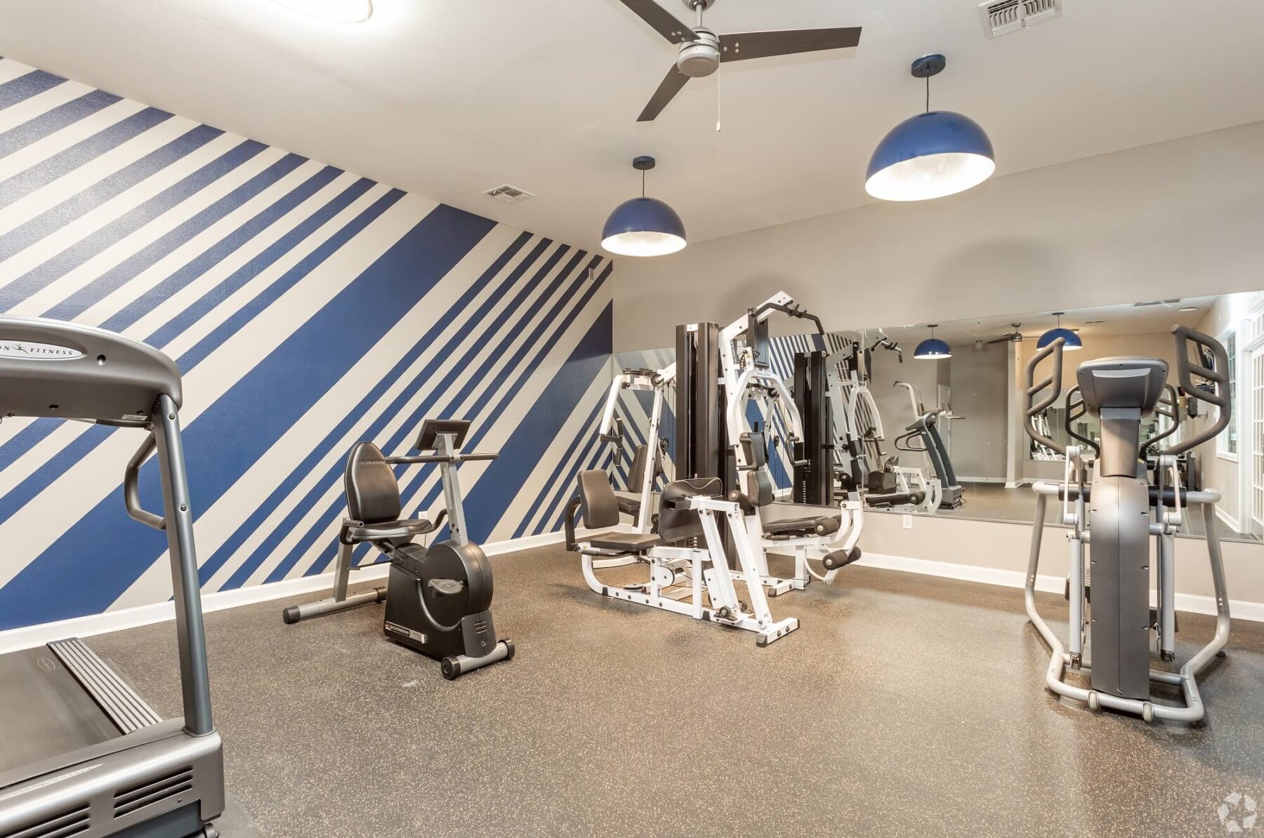Fitness room with large wall mirror and various cardio and strength equipment