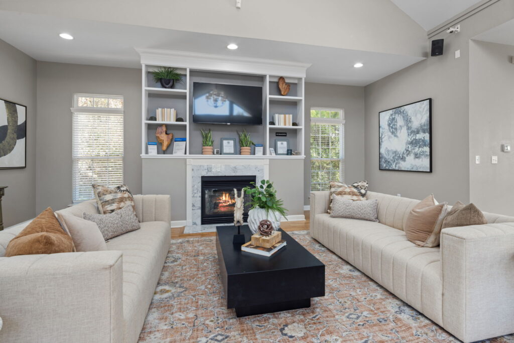 Clubhouse space with fireplace, armchair seating, and two computer desks at Heritage Apartments for rent in Hillsborough, NC.